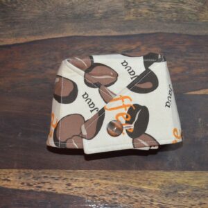 Rozkládací miska má design s motivem kávových zrn. Miska je vyrobena z látky s ilustracemi kávových zrn a textem "coffee" a "java" v oranžové barvě. Miska se zapíná na knoflík