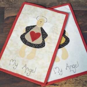 Prostírání "My Angel" obsahuje dva kusy látkových prostírání s designem anděla držícího červené srdce. Anděl je vytvořen z různých látkových vzorů
