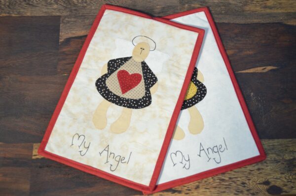 Prostírání "My Angel" obsahuje dva kusy látkových prostírání s designem anděla držícího červené srdce. Anděl je vytvořen z různých látkových vzorů