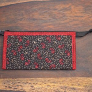 Kosmetická taštička je malá a má černou látku s červeným a béžovým paisley vzorem. Je lemována červenou látkou a má černý zip s úchytem. Tento design a barevná kombinace činí taštičku vizuálně atraktivní a praktickou pro uložení malých kosmetických předmětů. 1